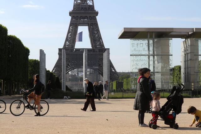 Las personas y las familias caminan por los Campos de Marte junto a la Torre Eiffel, en París, el 11 de mayo de 2020, el primer día de la reducción de las medidas de bloqueo de Francia durante 55 días para frenar la propagación de la pandemia. (Foto: AFP/Ludovic Marin)