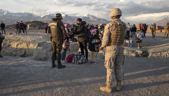 Una policía fronteriza chilena controla a los migrantes que cruzaron ilegalmente a Chile desde la frontera con Bolivia, en Colchane, el 3 de febrero de 2022. (Foto: DIEGO REYES / AFP)