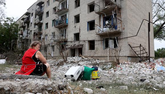 Una mujer, residente local, se sienta junto a sus pertenencias fuera de un edificio que fue parcialmente destruido tras un bombardeo en Chasiv Yar, Ucrania oriental, el 10 de julio de 2022. (Foto de Anatolii Stepanov / AFP)
