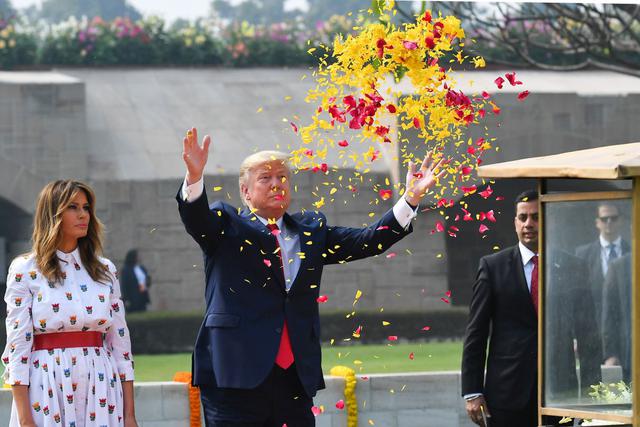 El presidente de los Estados Unidos, Donald Trump, rocía pétalos de flores mientras la Primera Dama Melania Trump observa mientras rinde homenaje a Raj Ghat, el monumento al icono de la independencia india Mahatma Gandhi, en Nueva Delhi. (AFP)