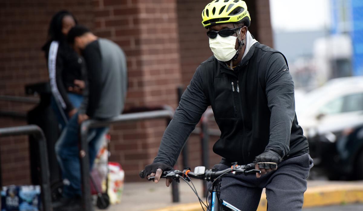 Un hombre con una máscara para tratar de prevenir la propagación de COVID-19, conocido como coronavirus, llega en bicicleta a un supermercado en Washington, DC. (Foto: AFP/Saul Loeb)