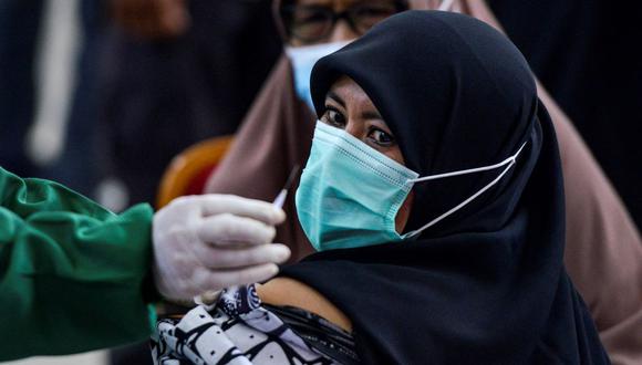 Una mujer observa una dosis de la vacuna Sinovac contra el coronavirus durante una vacunación masiva en Sibreh, provincia de Aceh, Indonesia. (Foto de CHAIDEER MAHYUDDIN / AFP).