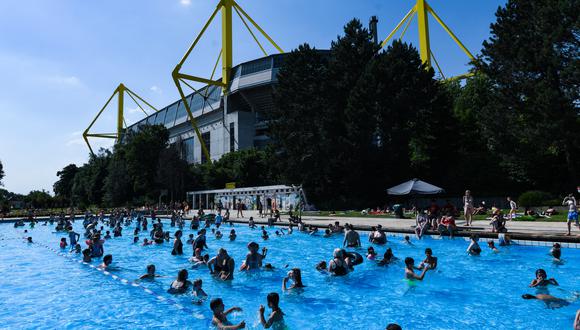 El estadio Signal Iduna Park se ve al fondo mientras los visitantes se quedan en la piscina pública 'Volksbad' en Dortmund, en un soleado 17 de junio de 2021. (Foto de Ina FASSBENDER / AFP)