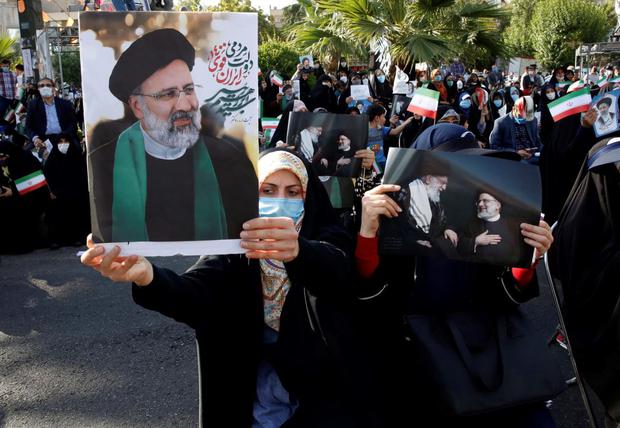 Mujeres simpatizantes del candidato presidencial iraní Ebrahim Raisi sostienen fotografías que lo representan durante un mitin de campaña electoral en Teherán. (EFE / EPA / ABEDIN TAHERKENAREH).