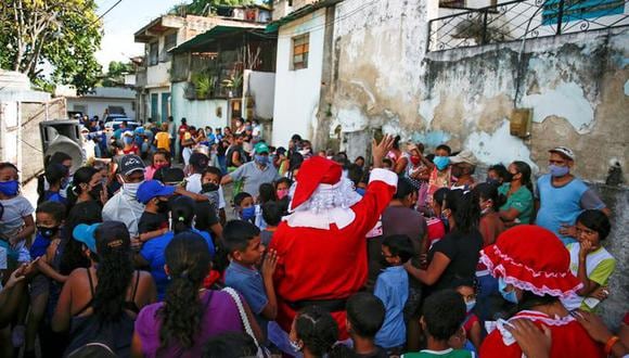 Un hombre disfrazado de Santa Claus, de la iniciativa privada "Santa en las calles", saluda a los vecinos antes de repartir alimentos y donar ropa a familias necesitadas, en un barrio de bajos recursos de Guarenas, al este de Caracas, Venezuela el 19 de diciembre. 2020. Foto tomada el 19 de diciembre de 2020 REUTERS/Fausto Torrealba