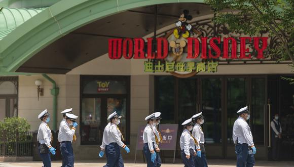 Los miembros del personal caminan en Disneytown en Shanghai el 16 de junio de 2022, durante el primer día de reapertura de Disneytown y el Shanghai Disneyland Hotel luego de los cierres de Covid-19 en la ciudad. (Foto de AFP)