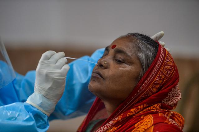 Un funcionario de salud recolecta una muestra de hisopado nasal de una mujer para una prueba rápida de antígeno para el coronavirus en un centro de recolección en el área de Samarnagar en Siliguri, India. En este país los muertos ascienden a 73.890. (Foto de DIPTENDU DUTTA / AFP). )(DIPTENDU DUTTA / AFP)