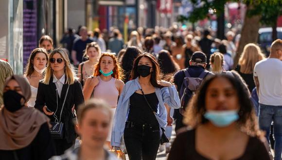 Los peatones, algunos con cubiertas faciales debido al coronavirus, pasan frente a las tiendas de Oxford Street en el centro de Londres, Reino Unido, el 7 de junio de 2021. (Niklas HALLE'N / AFP).