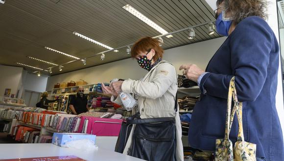 Una mujer que usa máscaras faciales desinfecta sus manos cuando ingresan a una tienda de telas en Ludwigsburg, sur de Alemania, en medio de la nueva pandemia de coronavirus COVID-19. (THOMAS KIENZLE / AFP)