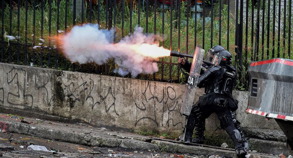 Un oficial de la policía antidisturbios lanza gases lacrimógenos a los manifestantes durante una protesta contra el gobierno en Cali, Colombia, el 10 de mayo de 2021. (Luis ROBAYO / AFP).