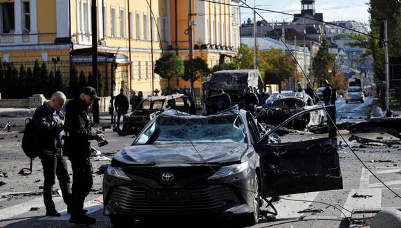 Los expertos de la policía examinan un automóvil destruido después de un ataque con misiles en el centro de la capital de Ucrania, Kiev, el 10 de octubre de 2022. (SERGEI CHUZAVKOV / AFP).
