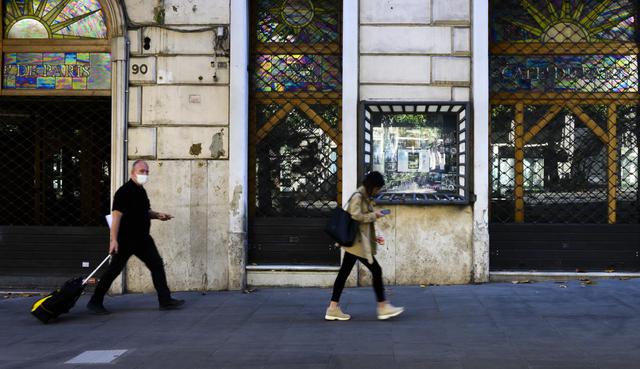 La gente pasa frente a un café cerrado en Via Veneto, en el centro de Roma, mientras el país alivia su bloqueo para frenar la propagación del coronavirus. (Tiziana FABI / AFP).