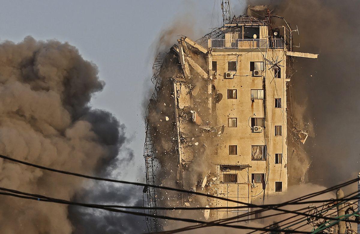 El humo se eleva desde la torre Al-Sharouk mientras se derrumba después de ser golpeada por un ataque aéreo israelí, en la ciudad de Gaza el 12 de mayo de 2021. (Mahmud Hams / AFP).