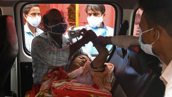 Los miembros de una familia atienden a una mujer inconsciente dentro de una camioneta en un centro de soporte de oxígeno gratuito para pacientes de coronavirus en Nueva Delhi, India. (Foto de Arun SANKAR). / AFP).