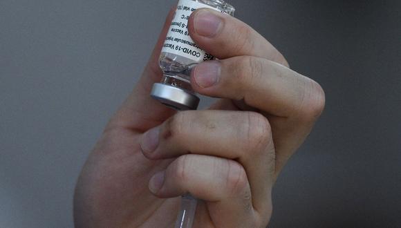 Un trabajador de la salud sostiene un frasco de la vacuna contra el coronavirus de AstraZeneca. (Foto referencial: Ted ALJIBE / AFP).