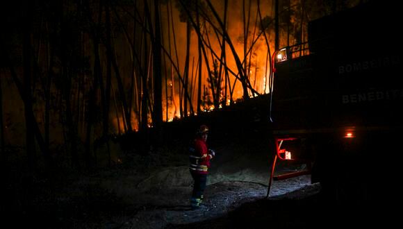 Un bombero se encuentra junto a un camión en el bosque durante un incendio forestal en Casais do Vento en Alvaiazere el 10 de julio de 2022. (Foto por PATRICIA DE MELO MOREIRA / AFP)