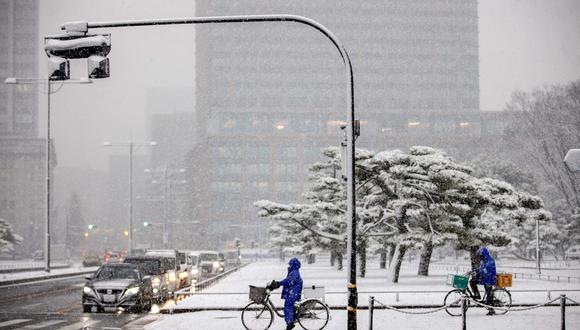 La gente anda en bicicleta por una calle nevada de Tokio el 6 de enero de 2022 (Foto: Behrouz MEHRI / AFP).