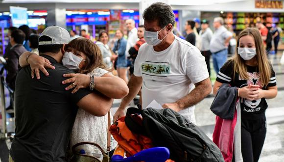Pasajeros con mascarilla como medida preventiva contra la propagación del coronavirus COVID-19 arriban al Aeropuerto Internacional de Ezeiza en Buenos Aires. (AFP / Ronaldo SCHEMIDT).