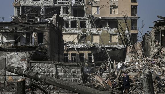Una pareja camina frente a las casas destruidas por los bombardeos en Kharkiv, durante la invasión militar rusa lanzada contra Ucrania. (Foto de Aris Messinis / AFP)