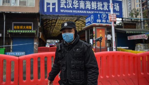 Un oficial de policía de China hace guardia fuera del mercado mayorista de mariscos de Huanan, donde se detectó el coronavirus en Wuhan, el 24 de enero de 2020. (Foto de Hector RETAMAL / AFP).