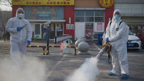 Los trabajadores que usan trajes para materiales peligrosos desinfectan las instalaciones de un mercado en el distrito Daxing de Beijing el 21 de enero de 2021. (Foto: Noel Celis / AFP)