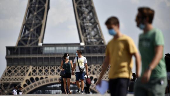 Personas con mascarillas caminan frente a la Torre Eiffel, como parte de las medidas para contener la propagación del coronavirus en París (Francia). (EFE/EPA/Julien de Rosa).