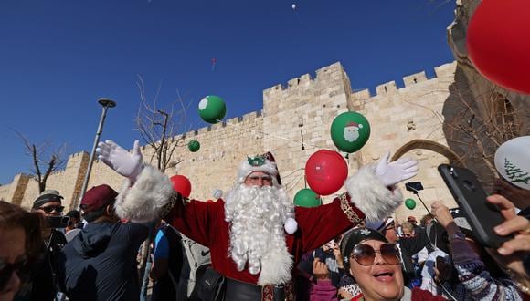 El palestino Issa Kassissieh, vestido como Santa Claus, posa para fotos con turistas y peregrinos en la Puerta de Jaffa en la Ciudad Vieja de Jerusalén, unas semanas antes de las próximas vacaciones de Navidad el 2 de diciembre de 2022. (Foto de AHMAD GHARABLI / AFP)