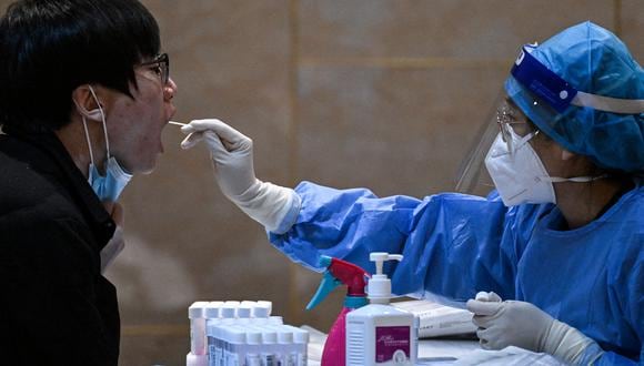 Un trabajador de la salud toma una muestra de hisopo de un periodista para hacerle la prueba del coronavirus Covid-19, la noche anterior al 14º Comité de la Conferencia Consultiva Política del Pueblo Chino (CCPPCh) en Beijing el 3 de marzo de 2023. (Foto de NOEL CELIS / AFP )