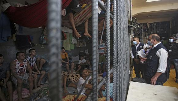 El ombudsman colombiano Carlos Camargo (D) mira a los presos en una celda durante una visita a un centro de detención temporal en Cali, Colombia, el 31 de marzo de 2022. (Foto de Paola MAFLA / AFP)