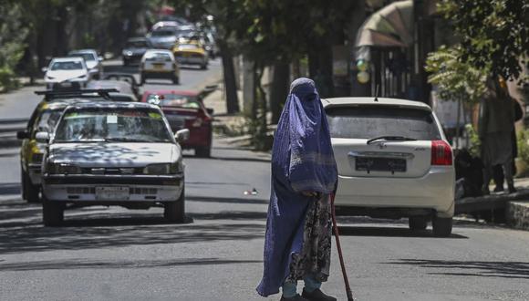 Una mujer vestida con burka pide limosna a los viajeros mientras se encuentra en medio de una carretera en Kabul el 6 de agosto de 2021 (Foto de SAJJAD HUSSAIN / AFP).
