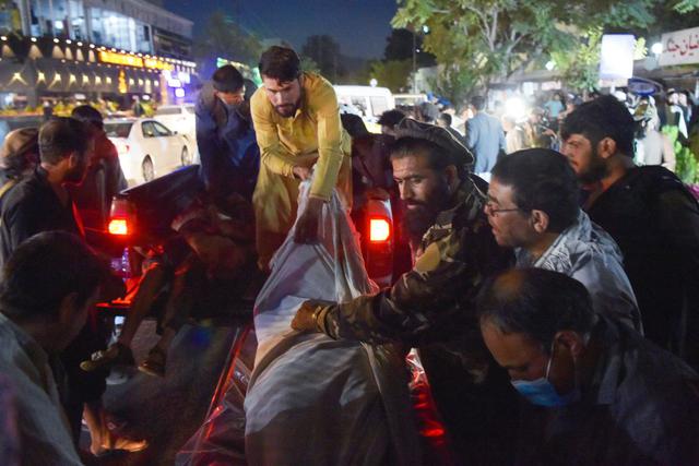 Voluntarios y personal médico descargan cadáveres de una camioneta fuera de un hospital después de dos poderosas explosiones en Kabul (Afganistán). (Wakil KOHSAR / AFP).
