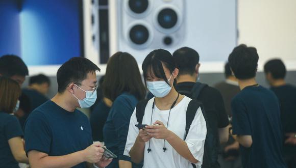 Un cliente (derecha) prueba un teléfono móvil iPhone 13 recién lanzado en una tienda Apple en Hangzhou, en la provincia oriental china de Zhejiang, el 24 de septiembre de 2021. (Foto de AFP) / China OUT