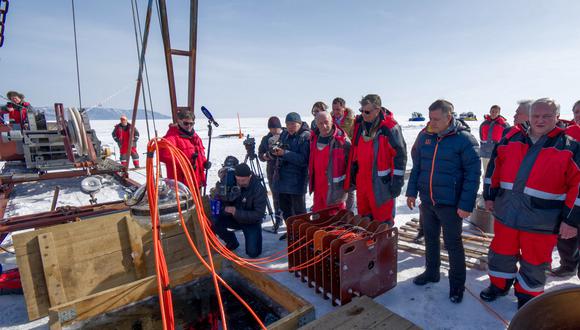 Científicos y funcionarios observan cómo el telescopio de neutrinos submarino se sumerge en el agua del lago Baikal. (Foto: AFP/Institute for Nuclear Research)