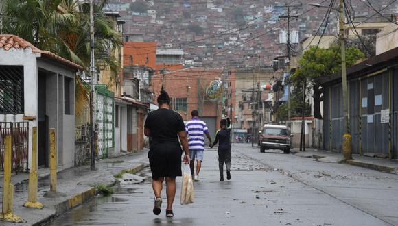 Se ve a personas paseando por la calle durante enfrentamientos entre la Policía Nacional Bolivariana y presuntos integrantes de una banda criminal en los alrededores del barrio La Cota 905 de Caracas, el 9 de julio de 2021. (Yuri CORTEZ / AFP).