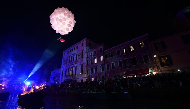 Dos enamorados endulzaron la noche con un tierno abrazo en el aire bajo la luna simbolizada por globos. (AFP).
