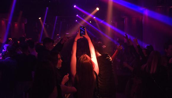 Una mujer toma una foto con su teléfono móvil mientras la gente baila en una discoteca en Barcelona el 11 de febrero de 2021. (Foto: Pau BARRENA / AFP)