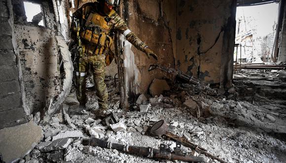 Un soldado ruso recoge las armas encontradas mientras patrullaba en el teatro dramático de Mariupol, bombardeado el 12 de abril de 2022. (Foto de Alexander NEMENOV / AFP)