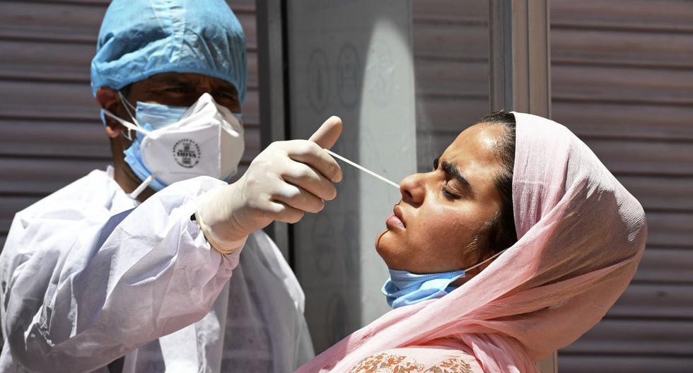 Un trabajador de la salud toma una muestra de hisopo nasal de una mujer para realizar la prueba del coronavirus Covid-19 en un centro de pruebas en Srinagar, India. (Foto de TAUSEEF MUSTAFA / AFP).