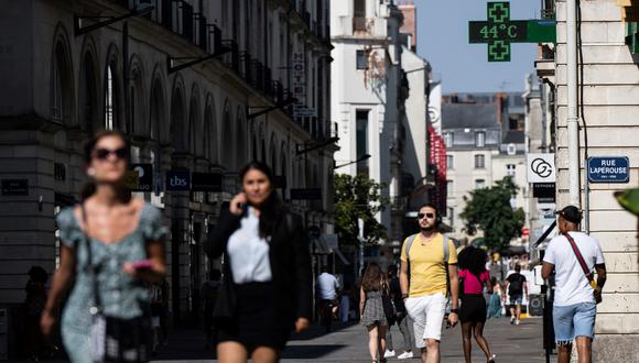 La gente camina por una calle en Nantes, el 18 de julio de 2022, mientras un letrero iluminado de una farmacia muestra una temperatura de 44 grados centígrados. (Foto: Loic VENANCE / AFP)