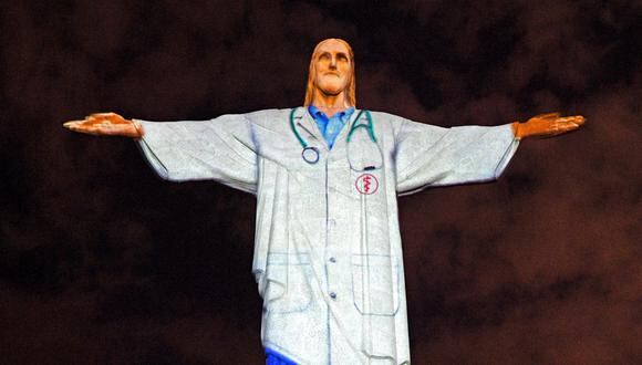 Vista de la mundialmente famosa estatua del Cristo Redentor con un uniforme médico proyectado en honor a todo el personal médico que lucha contra la pandemia de coronavirus COVID-19 en todo el mundo. (Foto: AFP/CARL DE SOUZA)