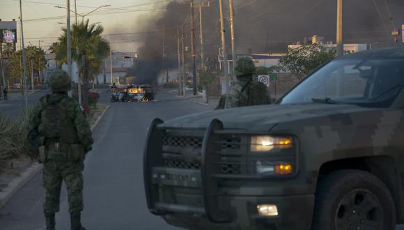 Soldados mexicanos montan guardia cerca de vehículos en llamas en una calle durante una operación para arrestar al hijo de Joaquín "El Chapo" Guzmán, Ovidio Guzmán, en Culiacán, estado de Sinaloa, México, el 5 de enero de 2023. (Foto por Juan Carlos CRUZ / AFP)
