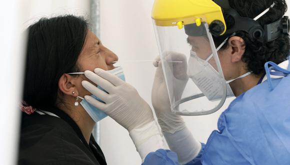 Un trabajador de salud toma una muestra nasal de COVID-19 de una mujer para una prueba de PCR dentro de una carpa en el Hospital General IESS Quito Sur, el 4 de enero de 2022. (Foto: Cristina Vega RHOR / AFP)
