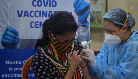 Un trabajador de la salud vacuna a una mujer con una inyección de la vacuna contra el coronavirus de Covishield en un club en Siliguri. (Diptendu DUTTA / AFP)