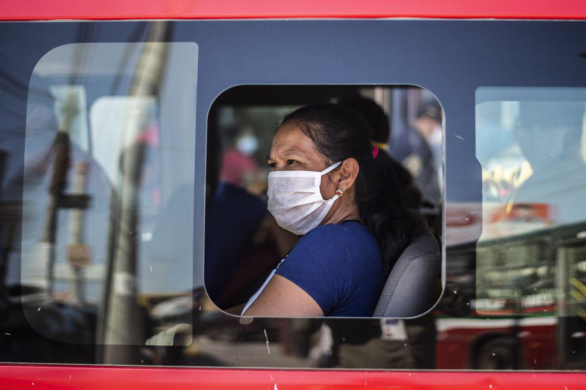 Una mujer con una mascarilla en una unidad de transporte público fuera del mercado de Ciudad de Dios, en Lima (Foto: ERNESTO BENAVIDES / AFP)