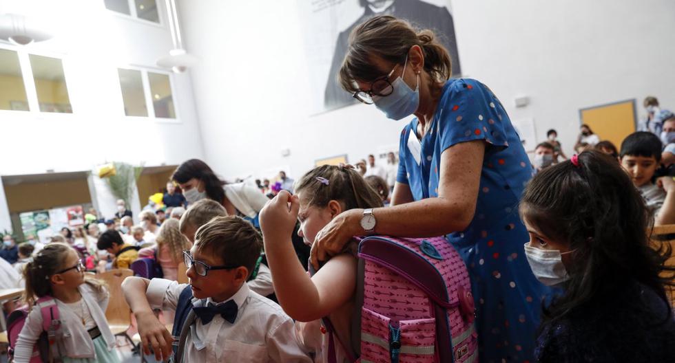 Imagen referencial. Una cuidadora que usa una mascarilla por el coronavirus ayuda a los alumnos con sus mochilas durante una ceremonia en una escuela primaria de Alemania. (EFE/EPA/FELIPE TRUEBA).