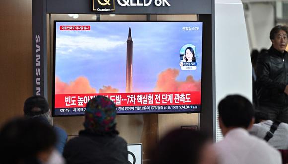 La gente se sienta cerca de un televisor que muestra una transmisión de noticias con imágenes de archivo de una prueba de misiles de Corea del Norte, en una estación de tren en Seúl el 6 de octubre de 2022. (Foto de Anthony WALLACE / AFP)