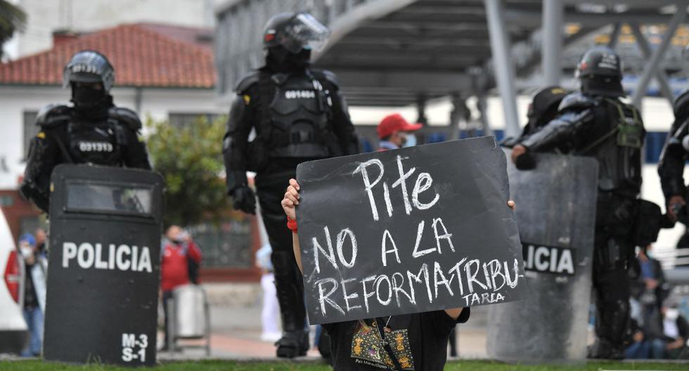Una mujer sostiene un cartel con la bandera colombiana que dice "No a la reforma tributaria" durante una manifestación en Bogotá, el 28 de abril de 2021. (JUAN BARRETO / AFP).