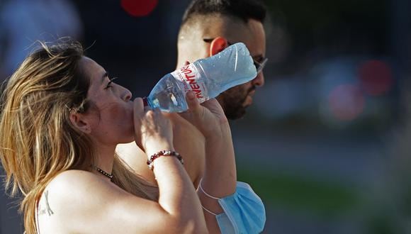 Una mujer bebe agua en un caluroso día de verano en Vicente López, cerca de Buenos Aires, el 13 de enero de 2022. (Foto de Alejandro PAGNI / AFP)