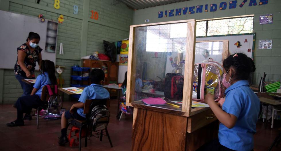 Allison López utiliza un pupitre diseñado por su padre y que le permite protección y mantener distancia para prevenir el coronavirus, en la escuela de Ciudad Delgado (El Salvador). (EFE/ Vladimir Chicas).