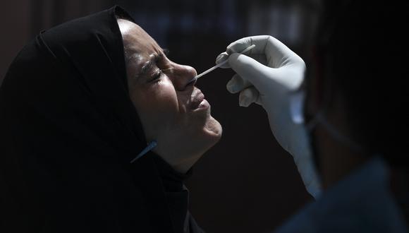 Un trabajador de la salud toma una muestra de una mujer para realizar la prueba del COVID-19 en un centro de pruebas en Srinagar. (Foto: TAUSEEF MUSTAFA / AFP)